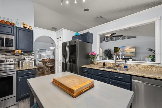 a kitchen with stainless steel appliances granite countertop a sink a stove and a refrigerator