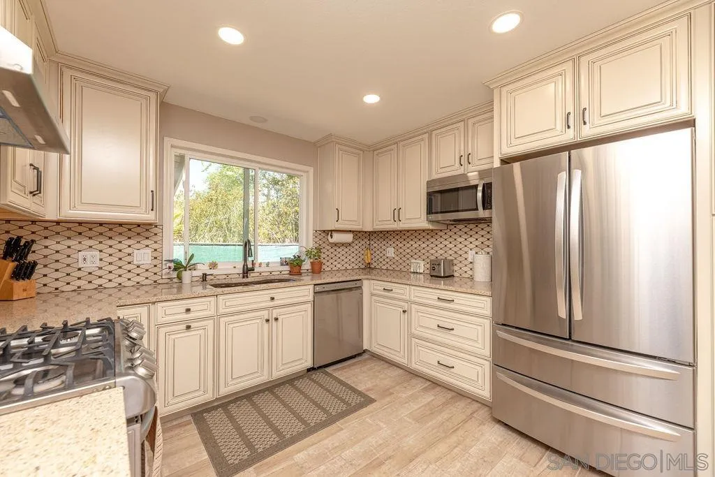 12317 Witt Road Poway, CA 92064 - Photo 14 of 43 a kitchen with granite countertop white cabinets and stainless steel appliances