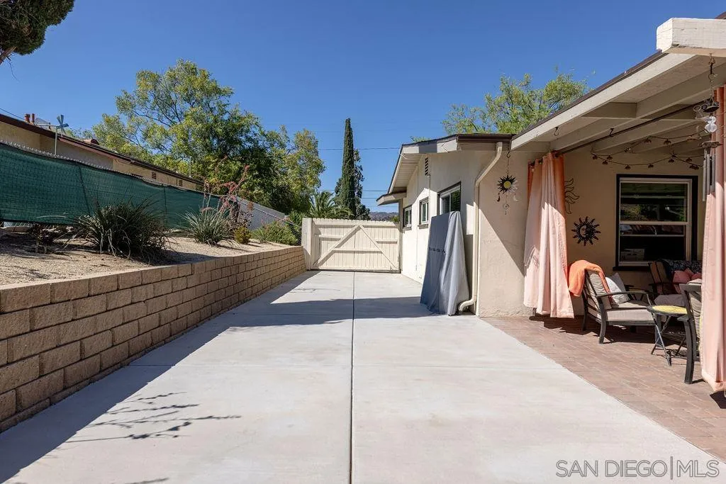 12317 Witt Road Poway, CA 92064 - Photo 43 of 43 a view of a patio with a table and chairs under an umbrella with potted plants