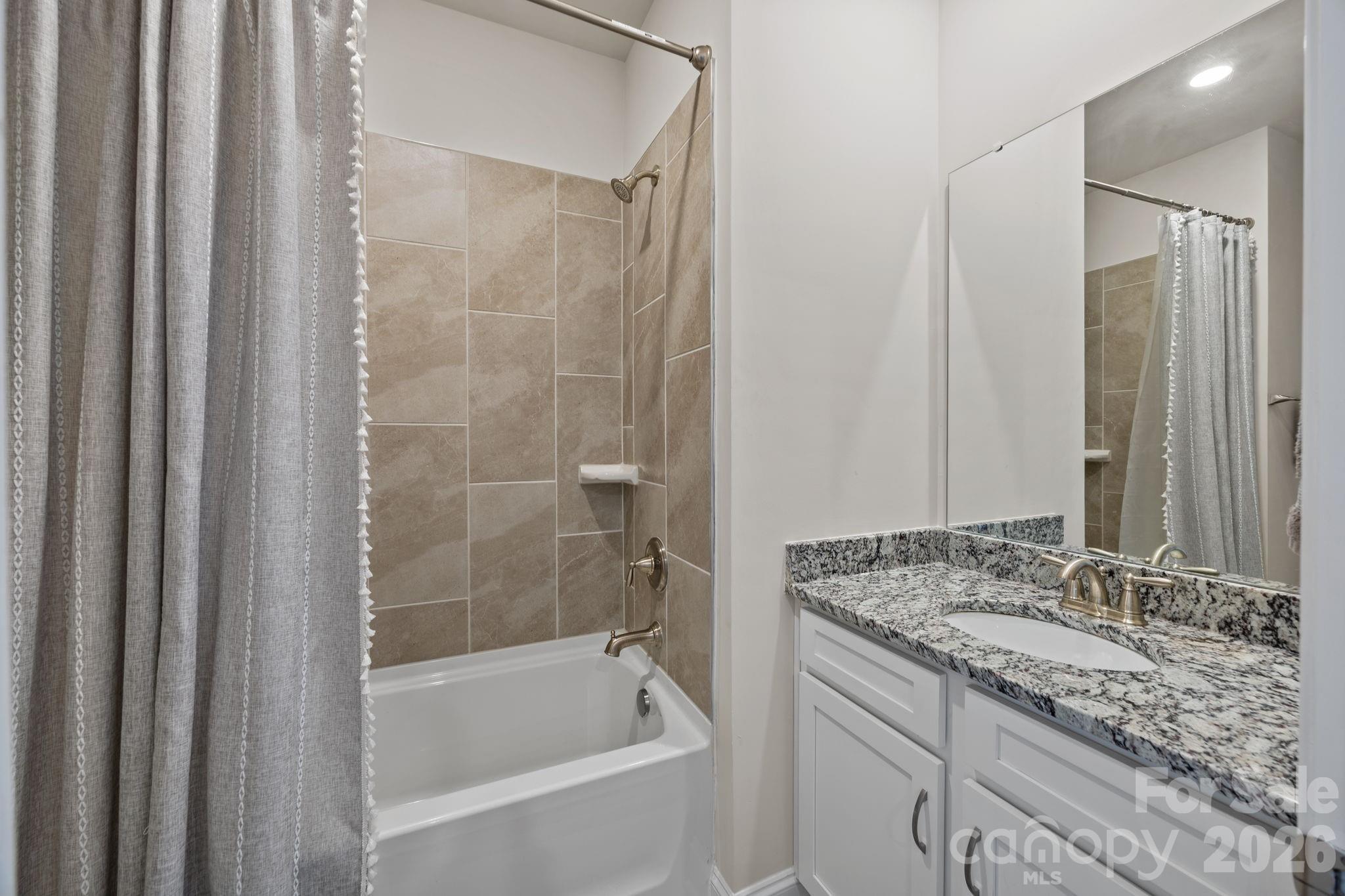 181 Brixham Loop Troutman, NC 28166 - Photo 19 of 28 a bathroom with a granite countertop sink and a bathtub