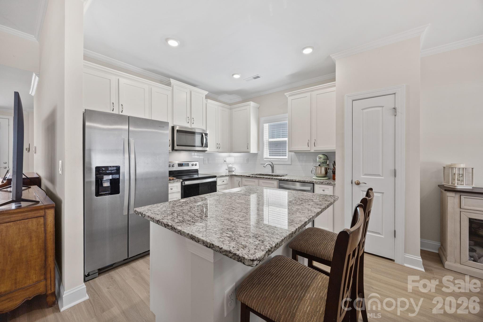 181 Brixham Loop Troutman, NC 28166 - Photo 6 of 28 a large kitchen with kitchen island a table and chairs