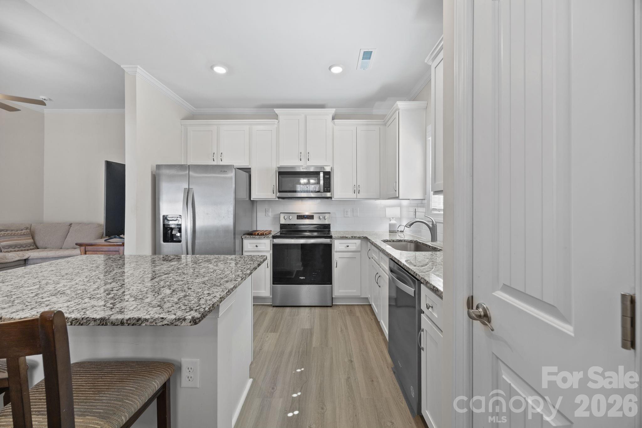 181 Brixham Loop Troutman, NC 28166 - Photo 7 of 28 a kitchen with kitchen island granite countertop a sink stove refrigerator and cabinets