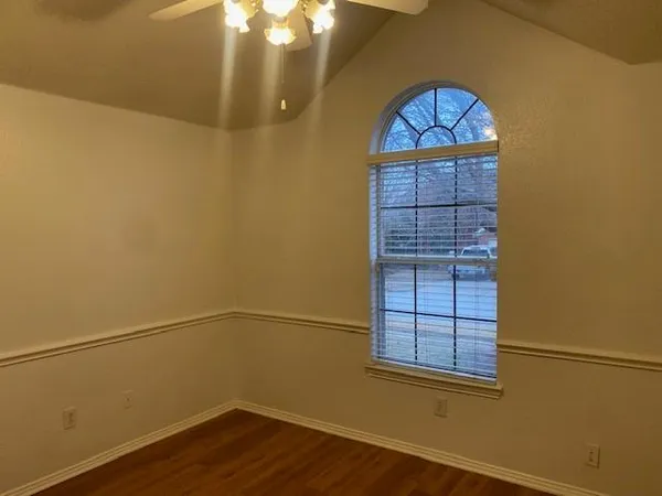a view of empty room with wooden floor and fan