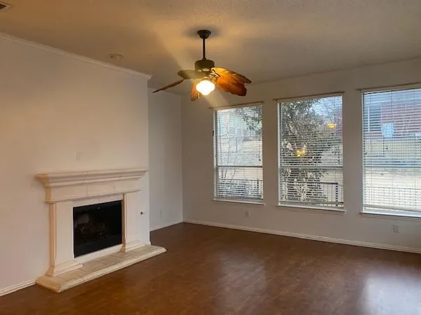 a view of an empty room with chandelier fan and fire place