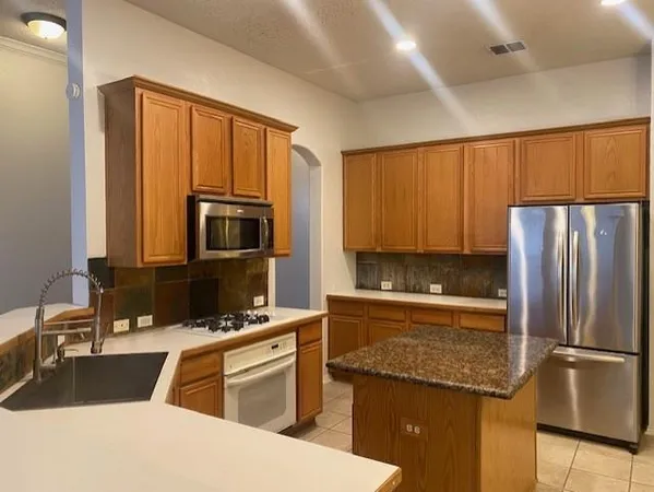 a kitchen with granite countertop a refrigerator stove and sink