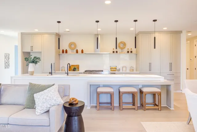 a living room with furniture kitchen view and a wooden floor