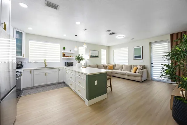 a large white kitchen with a large window a sink and a counter top space