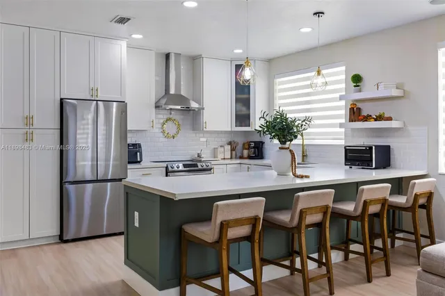 a kitchen with refrigerator and chairs in it