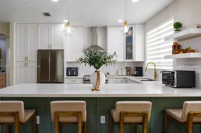 a kitchen with stainless steel appliances granite countertop a kitchen island and chairs in it