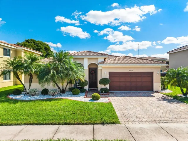 a front view of a house with a yard and potted plants