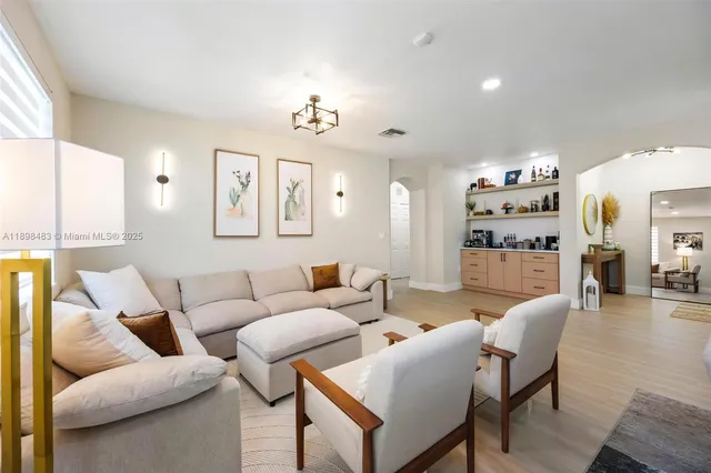 a living room with furniture kitchen view and a large window