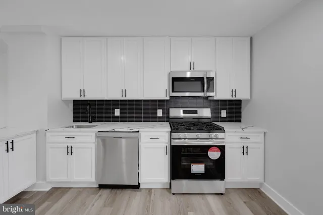 a kitchen with stainless steel appliances granite countertop a stove and white cabinets