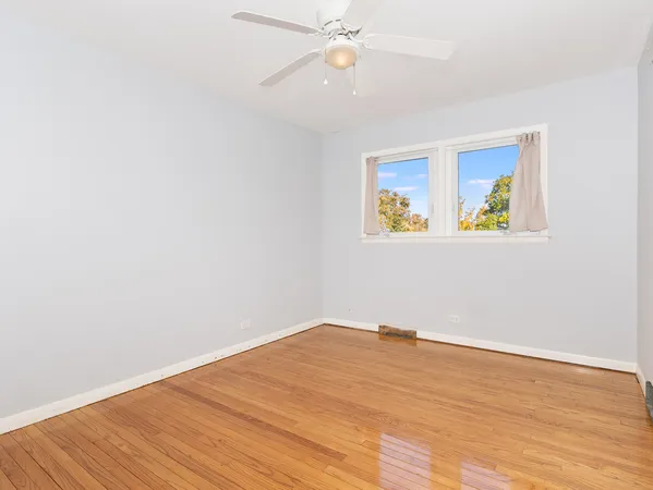 an empty room with wooden floor closet fan and windows