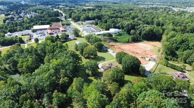 an aerial view of residential house with outdoor space and trees all around