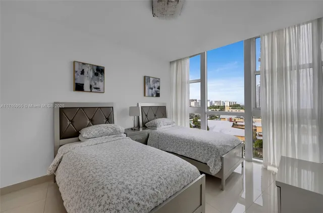 a bedroom with two beds and large window