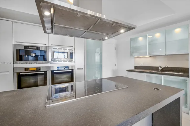 a modern kitchen with stainless steel appliances granite countertop a stove a sink and a refrigerator