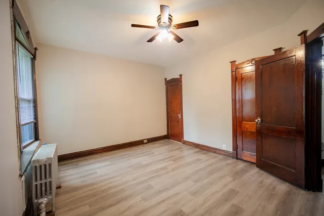 an empty room with wooden floor and a ceiling fan