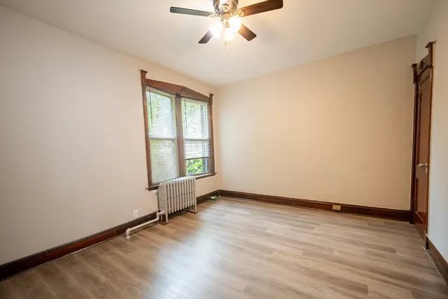an empty room with wooden floor fan and windows