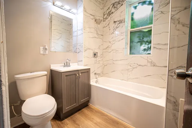 a bathroom with a granite countertop toilet sink and mirror