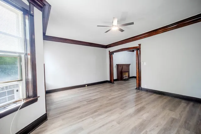 a view of an empty room with wooden floor and a window