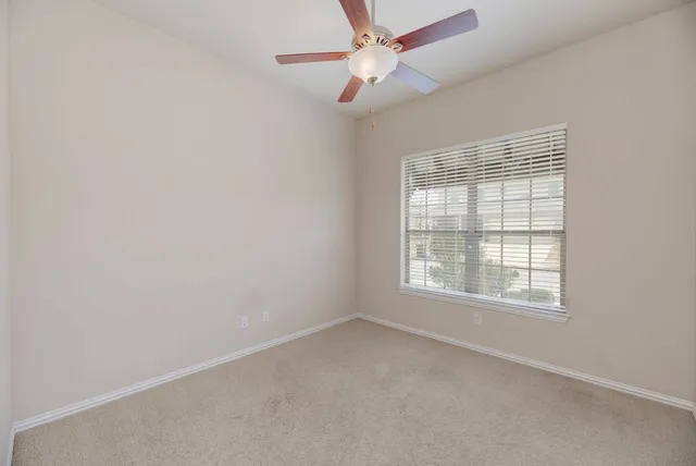 an empty room with a window and a fan
