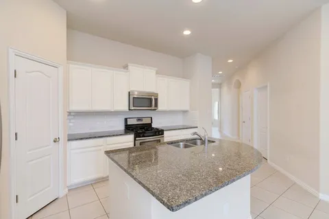 a kitchen with stainless steel appliances granite countertop a sink a refrigerator and a granite counter tops