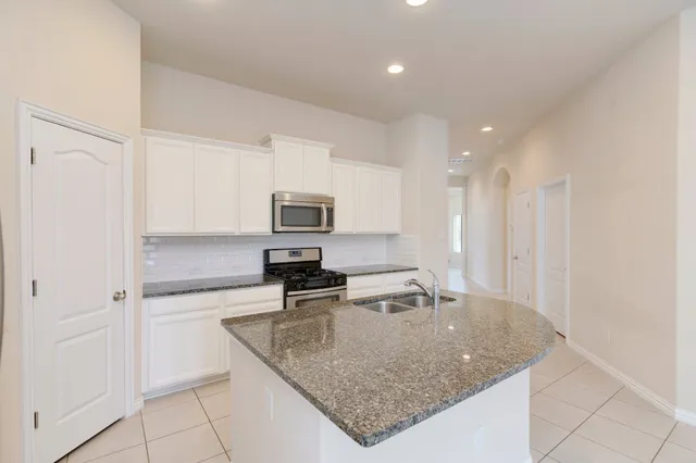 a kitchen with stainless steel appliances granite countertop a sink a refrigerator and a granite counter tops