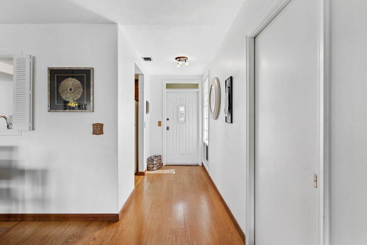 19867 Boca W Drive, Unit 3262 Boca Raton, FL 33434 - Photo 2 of 36 a hallway with sliding door and wooden floor