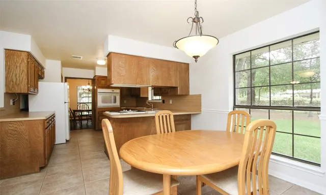 a kitchen with stainless steel appliances granite countertop a stove a refrigerator a sink a dining table and chairs with wooden floor