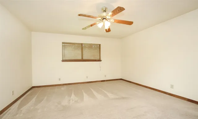 an empty room with a window and a ceiling fan
