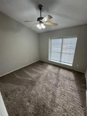 an empty room with a chandelier fan and windows