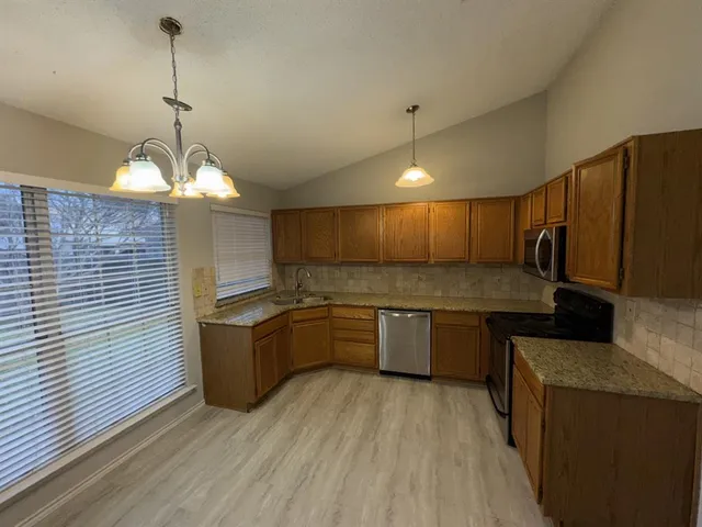 a kitchen with granite countertop a stove a sink dishwasher and a refrigerator