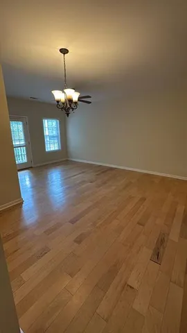 an empty room with wooden floor chandelier and windows