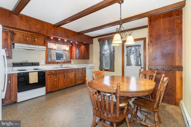 a kitchen with a dining table chairs stainless steel appliances and cabinets