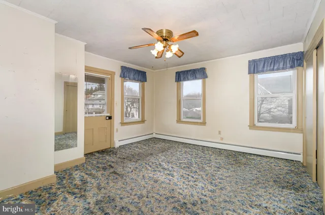 an empty room with windows and ceiling fan