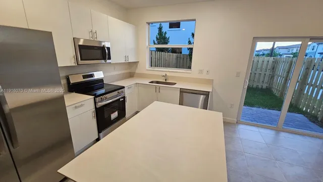 a kitchen with granite countertop a refrigerator stove and sink