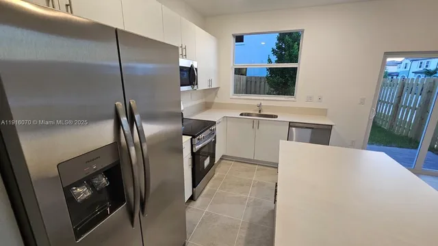 a kitchen with stainless steel appliances granite countertop a refrigerator a stove and a sink