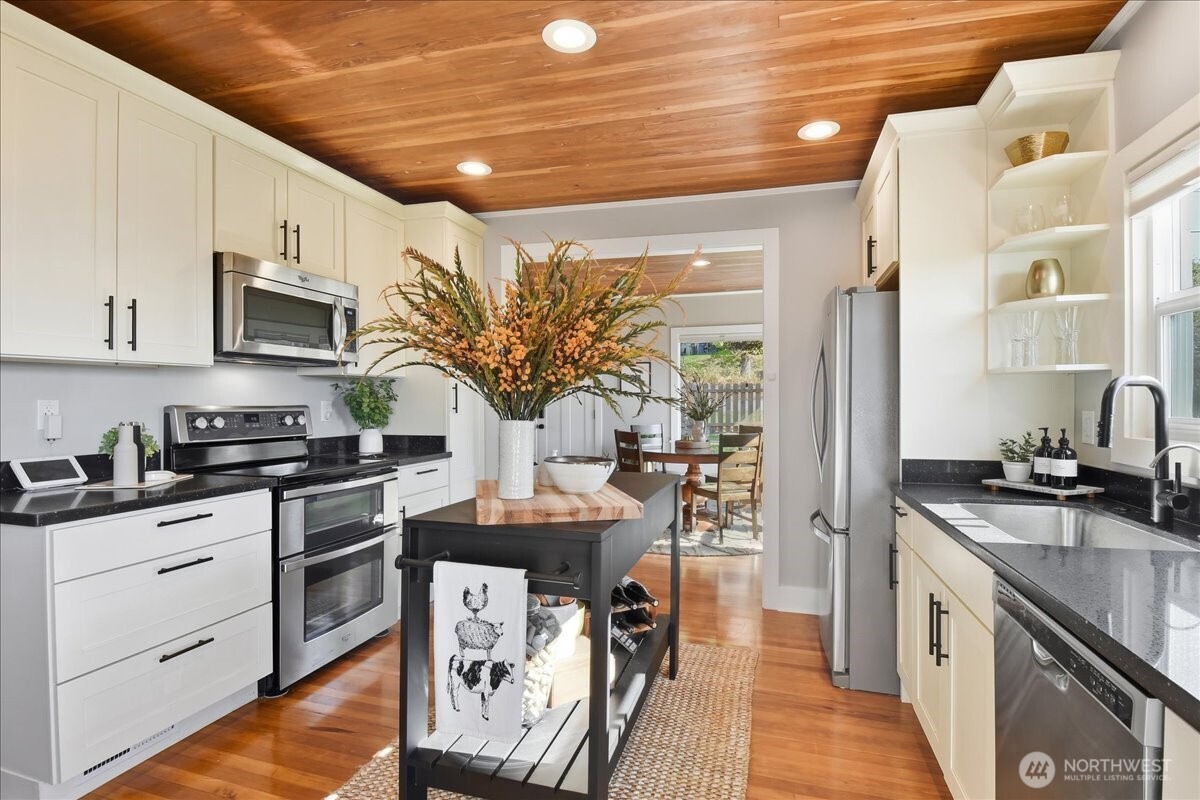7130 Foster Slough Road Snohomish, WA 98290 - Photo 14 of 38 a kitchen with stainless steel appliances granite countertop a stove top oven a sink dishwasher a dining table and chairs with wooden floor