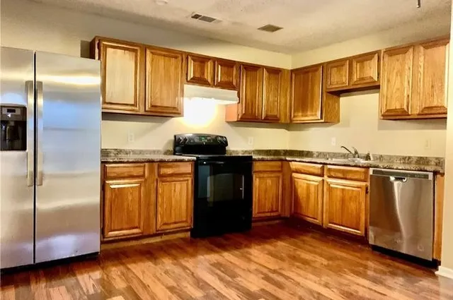 a kitchen with granite countertop a refrigerator stove and sink