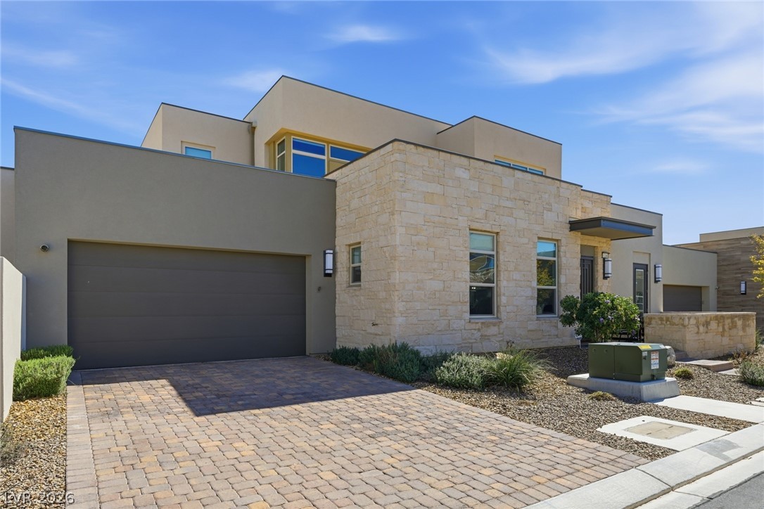 4246 Swift Street Las Vegas, NV 89135 - Photo 3 of 71 Modern home with decorative driveway, a garage, stone siding, and stucco siding