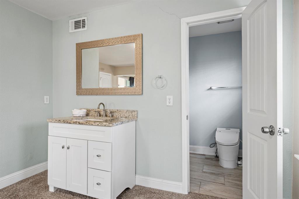 904 Treasure Road Garland, TX 75041 - Photo 19 of 27 a view of bathroom with a toilet sink vanity and a mirror