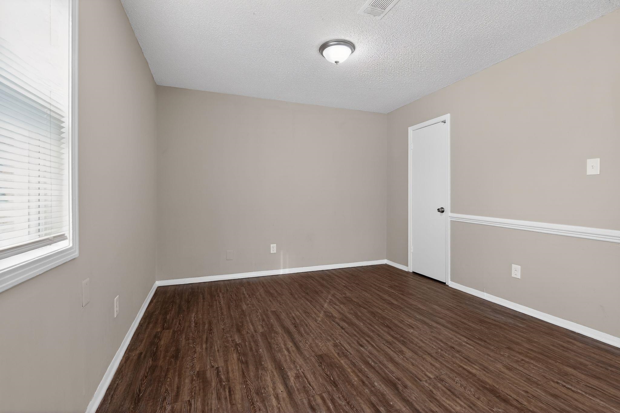 4212 Falcon Drive Memphis, TN 38109 - Photo 2 of 31 Spare room with dark wood-style floors, a textured ceiling, and healthy amount of natural light