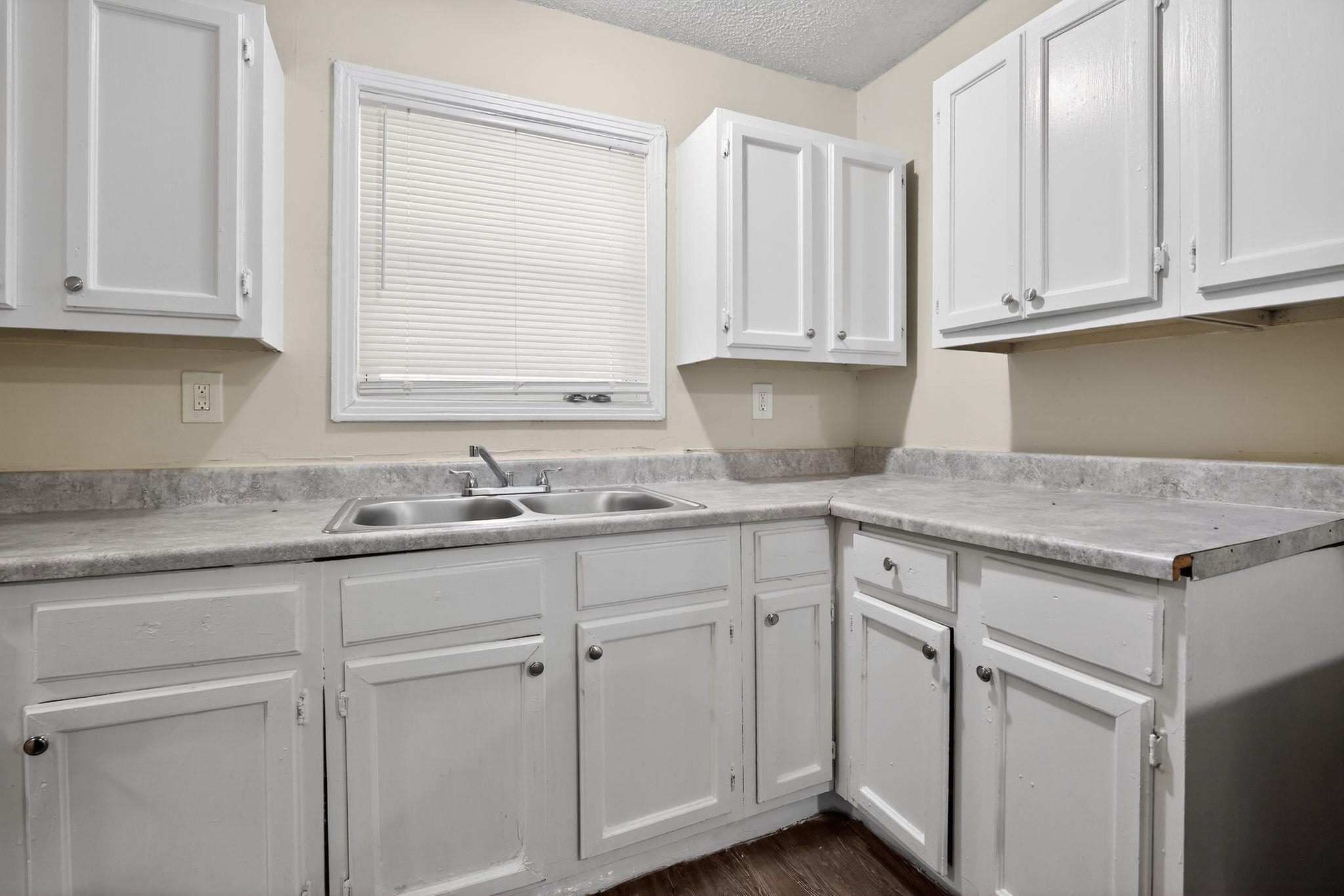 4212 Falcon Drive Memphis, TN 38109 - Photo 27 of 31 Kitchen featuring white cabinets, light countertops, a textured ceiling, and dark wood-style floors