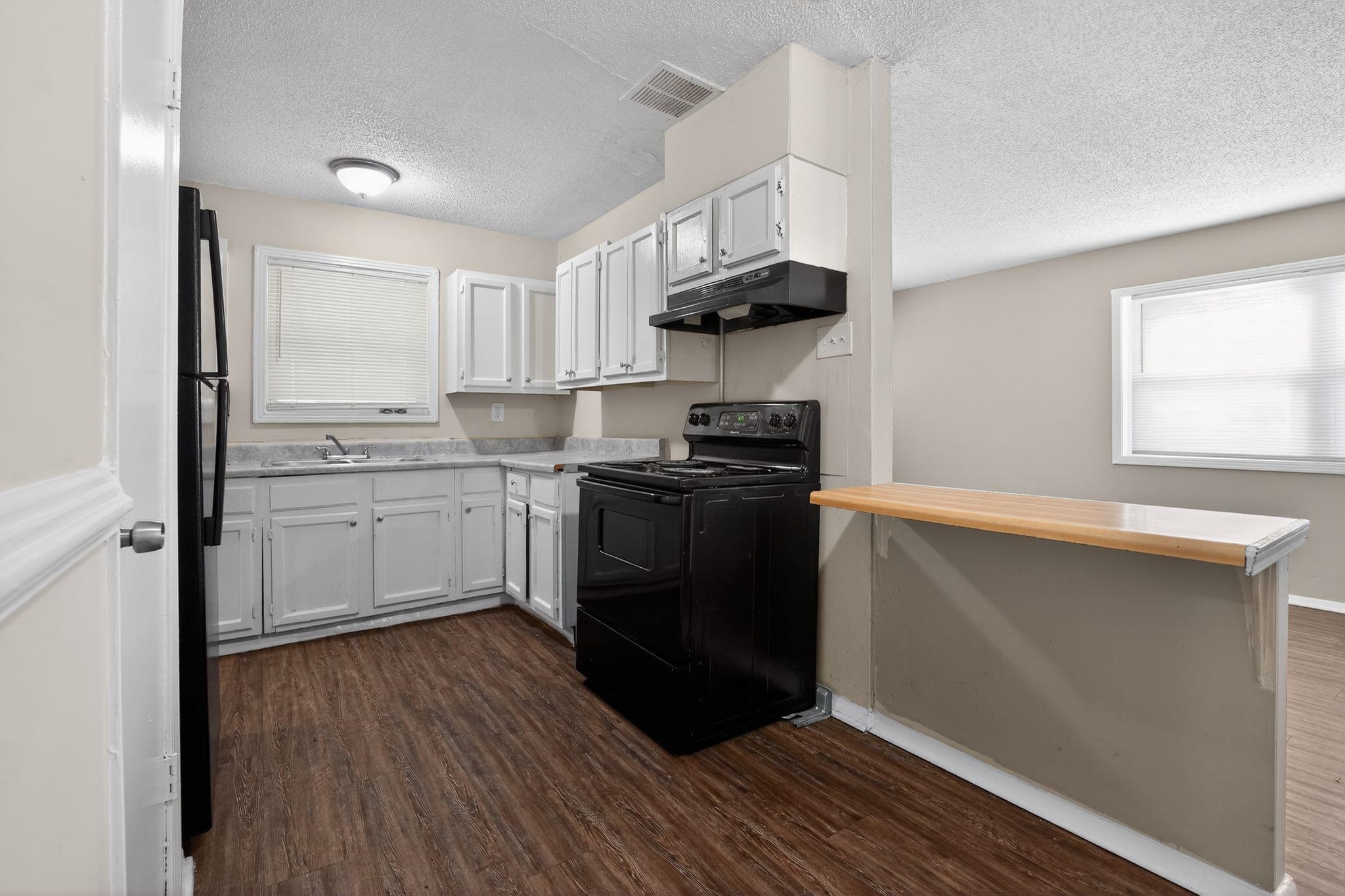 4212 Falcon Drive Memphis, TN 38109 - Photo 28 of 31 Kitchen featuring white cabinets, black appliances, light countertops, a textured ceiling, and dark wood-style floors