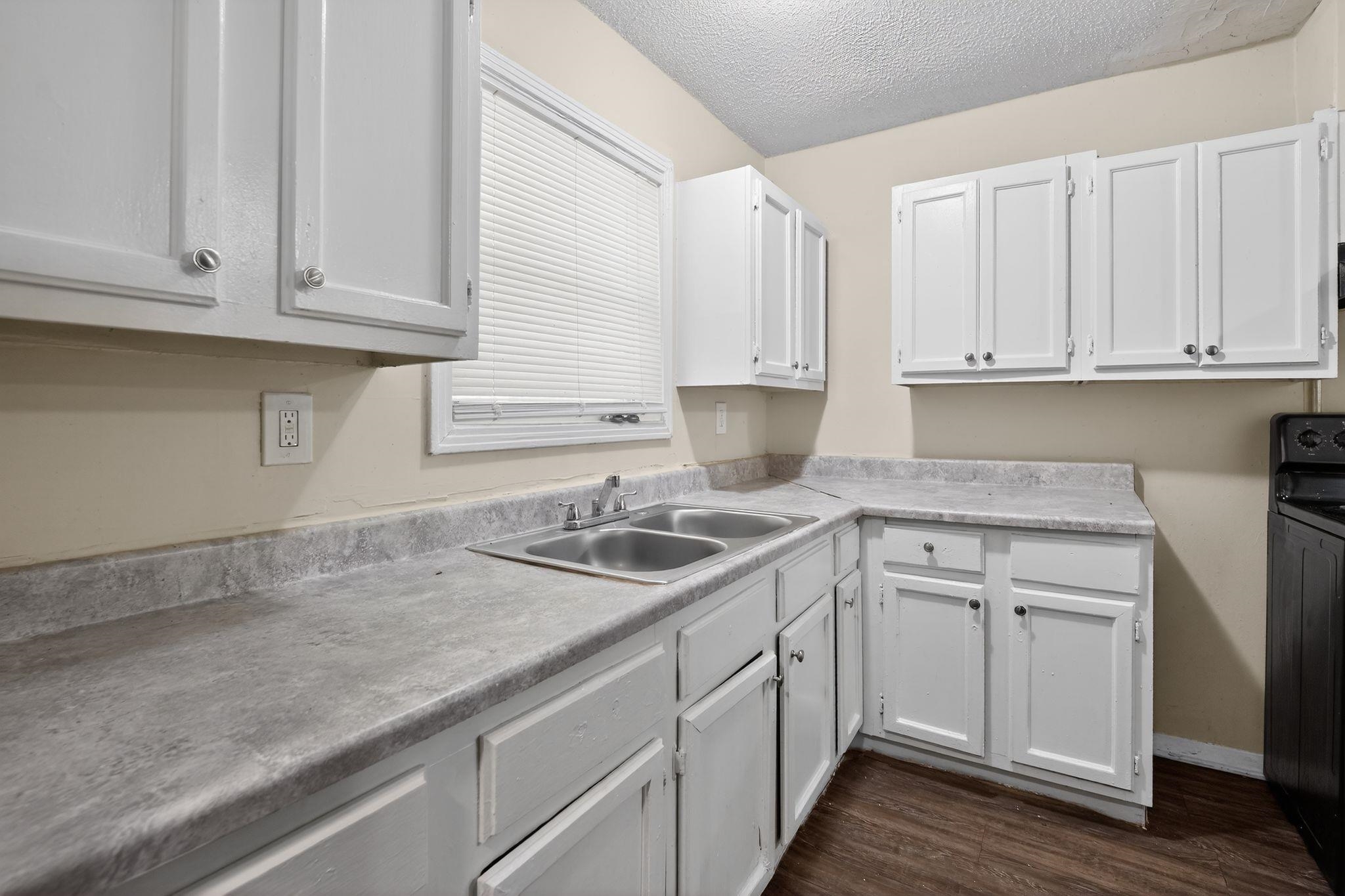 4212 Falcon Drive Memphis, TN 38109 - Photo 29 of 31 Kitchen with white cabinets, a textured ceiling, light countertops, black range, and dark wood-type flooring