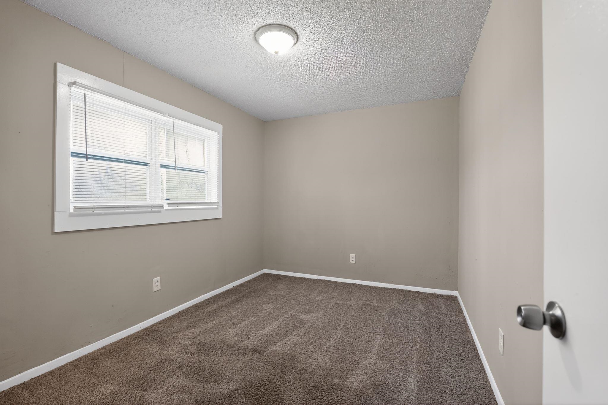 4212 Falcon Drive Memphis, TN 38109 - Photo 3 of 31 Empty room with a textured ceiling and dark colored carpet