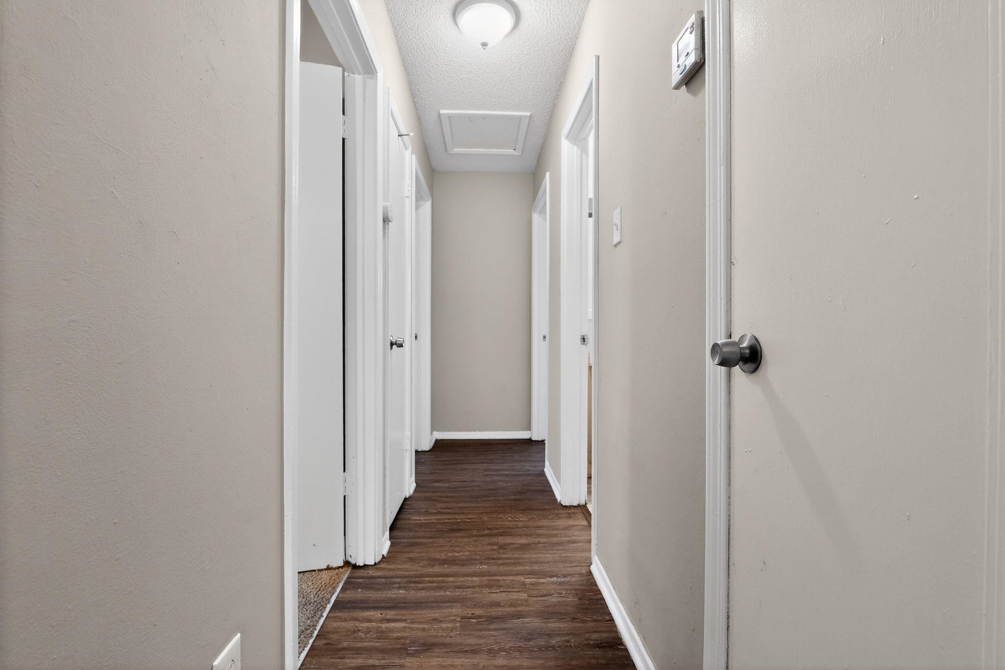4212 Falcon Drive Memphis, TN 38109 - Photo 9 of 31 Hall with attic access, a textured ceiling, and dark wood-style floors