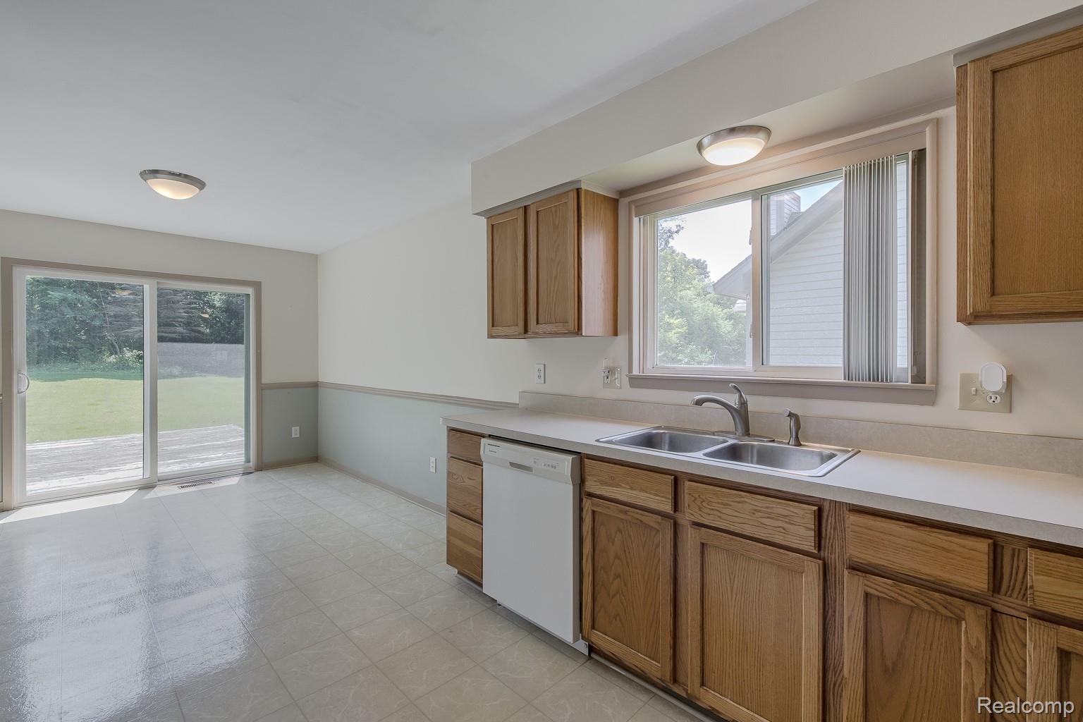 312 Reid Road Highland, MI 48357 - Photo 5 of 5 Kitchen area featuring wood cabinetry, a double basin stainless steel sink, and a white dishwasher