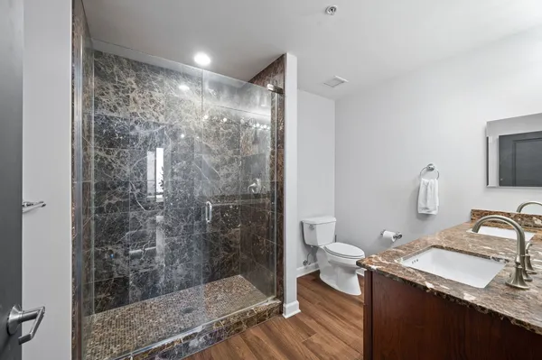 a bathroom with a granite countertop sink a toilet and shower