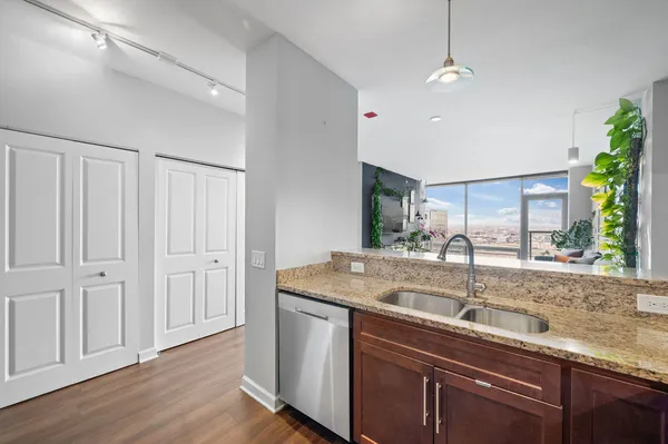 a kitchen with stainless steel appliances granite countertop a sink a counter space and a window